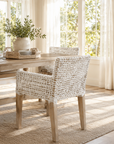 Dining room with wicker chairs and a table, natural light streaming in.