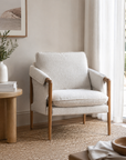 Beige armchair in a living room setting with a side table and decor items.