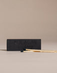 Kulala Living black matchbox with minimalist branding, featuring long wooden matches with black tips, set against a neutral backdrop for a refined aesthetic