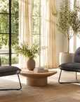 Modern living room with two dark gray chairs, a small round table, and decorative elements.