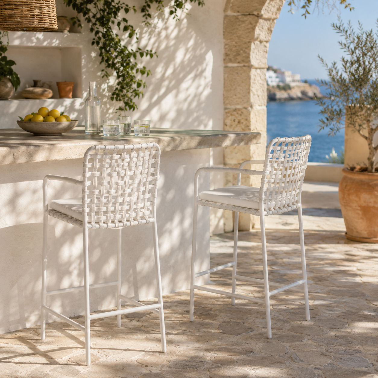 Outdoor setting with a table and two chairs near a stone wall and ocean view.