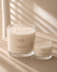 Two SOL Candle Co. Cashmere scented candles in clear glass jars, one large and one small, styled on a beige surface with soft window shadow patterns.