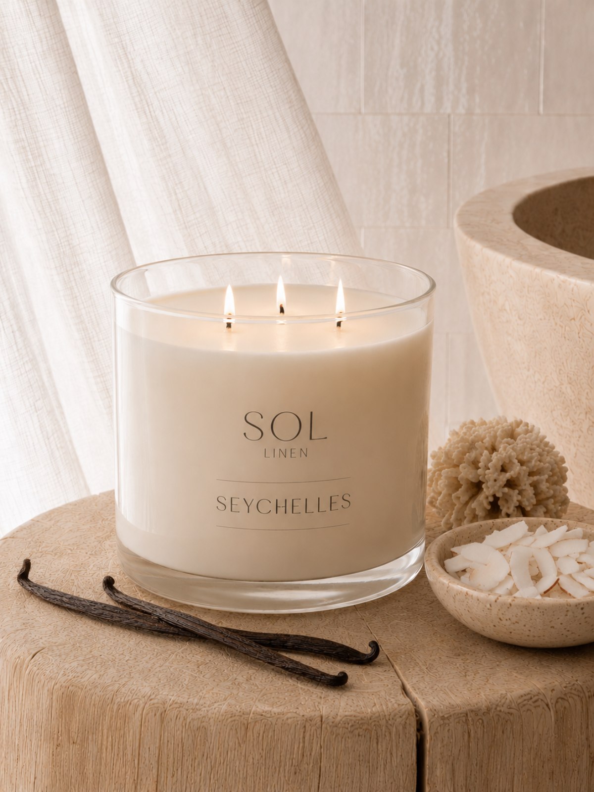 Scented candle labeled 'SOL Linen Seychelles' on a wooden surface with vanilla beans and a shell.