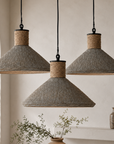 Three pendant lights hanging in a room with plants and a vase.