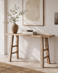 Wooden console table with a vase and books against a white wall