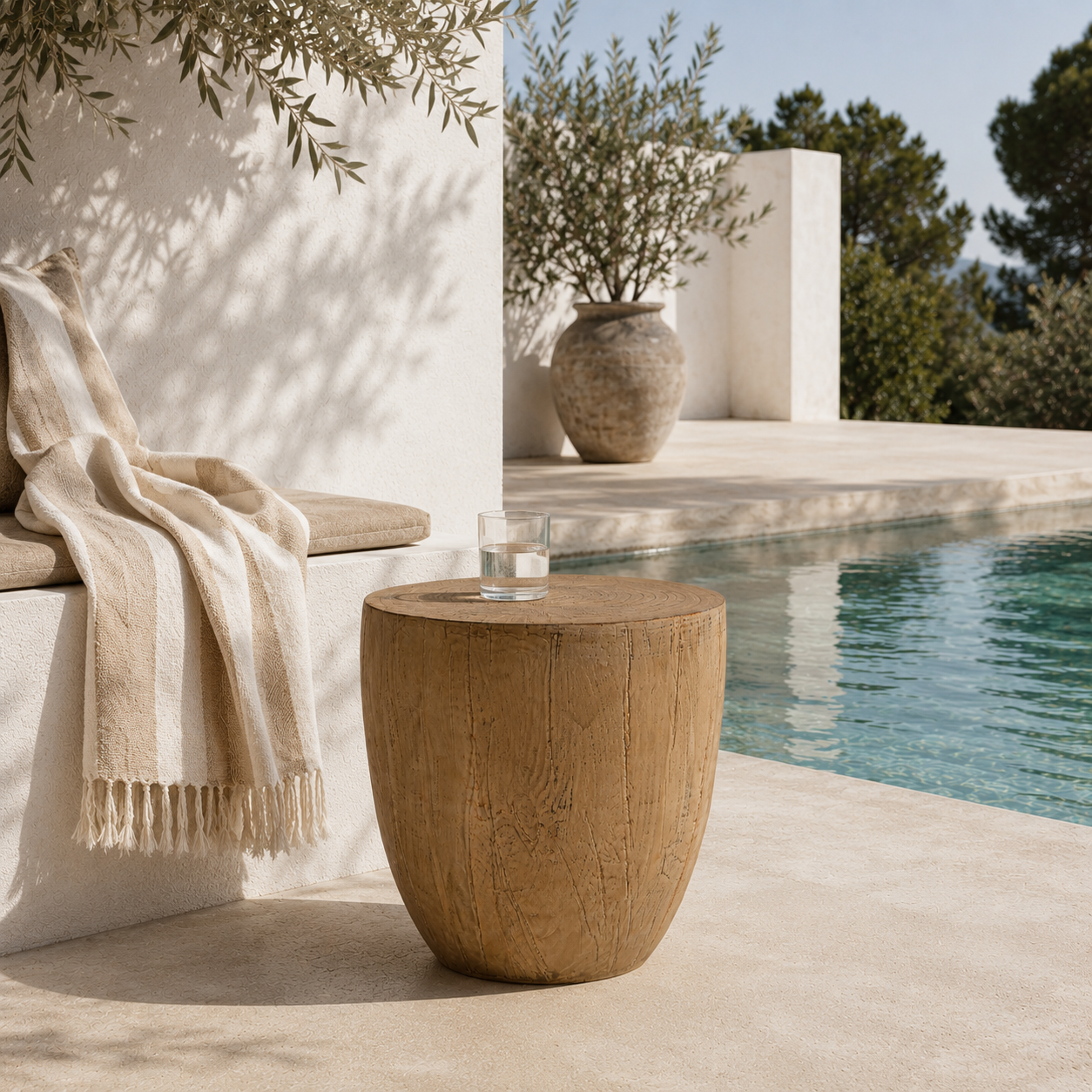 Wooden side table by a pool with a blanket and vase in the background