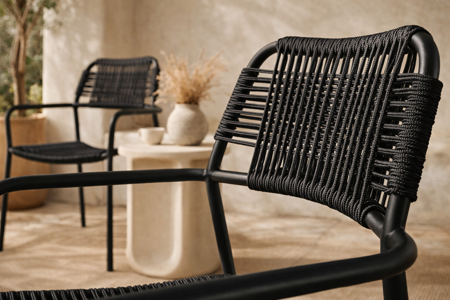 Modern outdoor dining chair featuring a black metal frame with a handwoven black rope seat and backrest, designed for sleek and contemporary alfresco dining