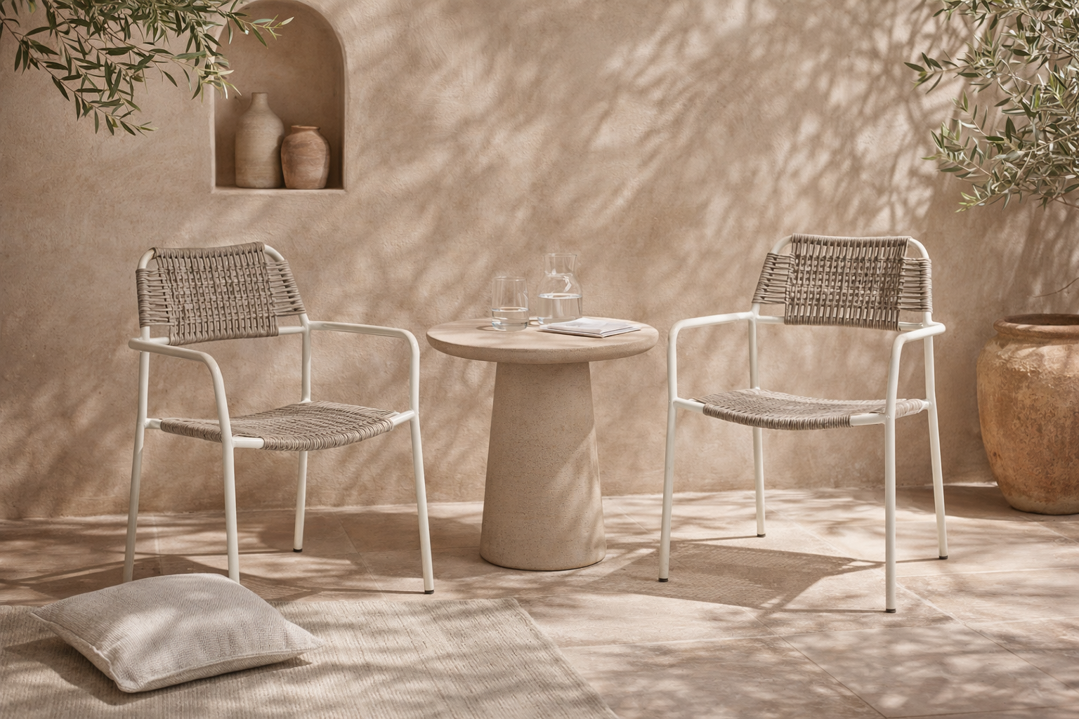 Amila armchair in white with natural rope weave styled in a sunlit mediterranean courtyard with textured walls and stone table