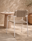 Amila armchair in white with natural rope weave styled in a sunlit mediterranean courtyard with textured walls and stone table