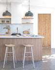 Bright modern kitchen with natural ashwood bar stools at a timber island, styled with sculptural pendant lights and soft neutral tones