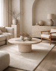 Ayanda coffee table in dune hydro dipped finish with round top and sculptural pedestal base styled in a warm neutral living room.