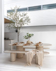 Ayanda dining table and bench in dune finish styled in a light filled outdoor space with natural textures and relaxed coastal dining atmosphere.