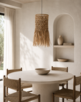 Bakonga Pendant in Natural suspended above a round dining table, bringing organic texture and warm handcrafted character to a calm contemporary dining space.