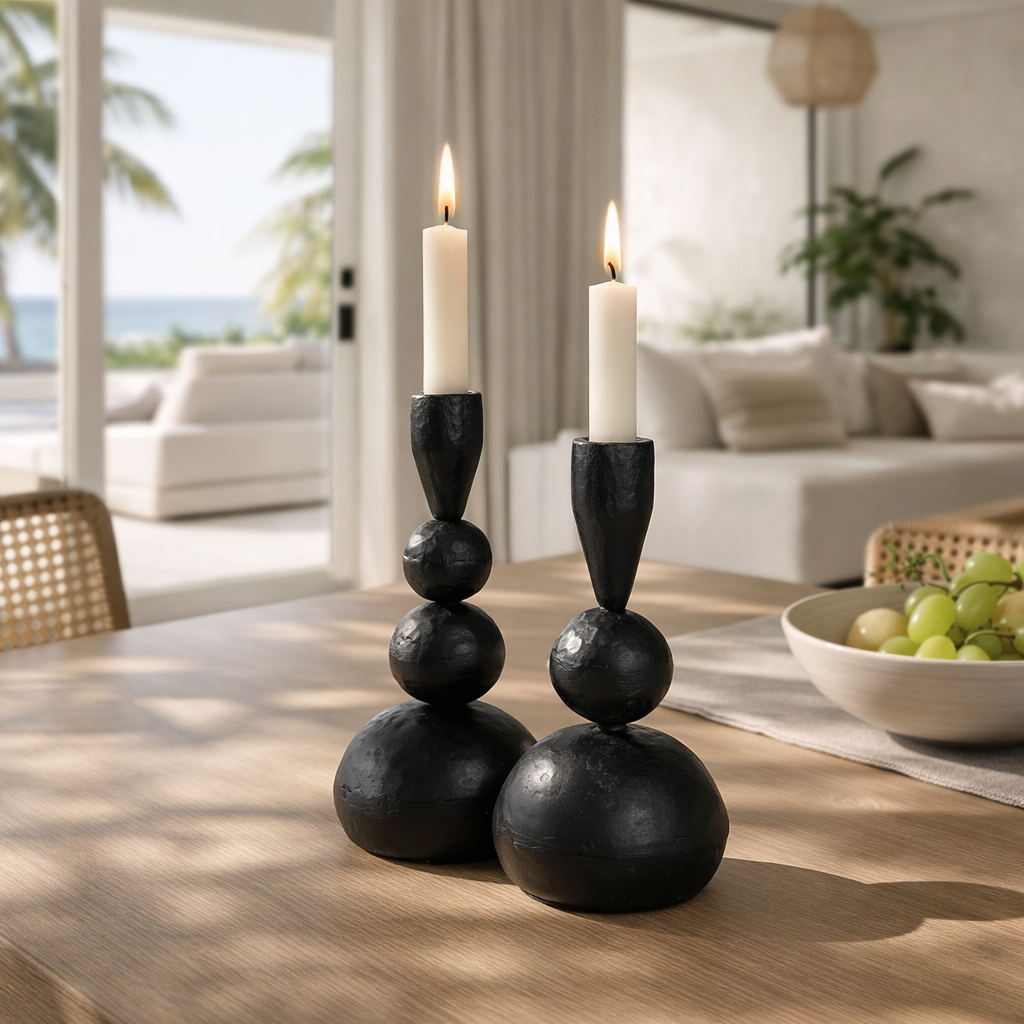 Black ball candle holders styled on a timber dining table with lit white taper candles