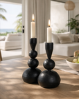 Black ball candle holders styled on a timber dining table with lit white taper candles