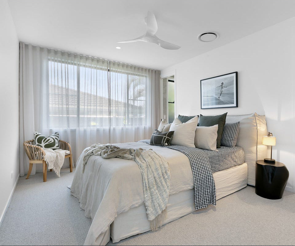 Serene bedroom featuring soft linen bedding in neutral tones, plush cushions, and a cosy throw, complemented by the Makena Chair in the corner, styled with a decorative cushion and blanket