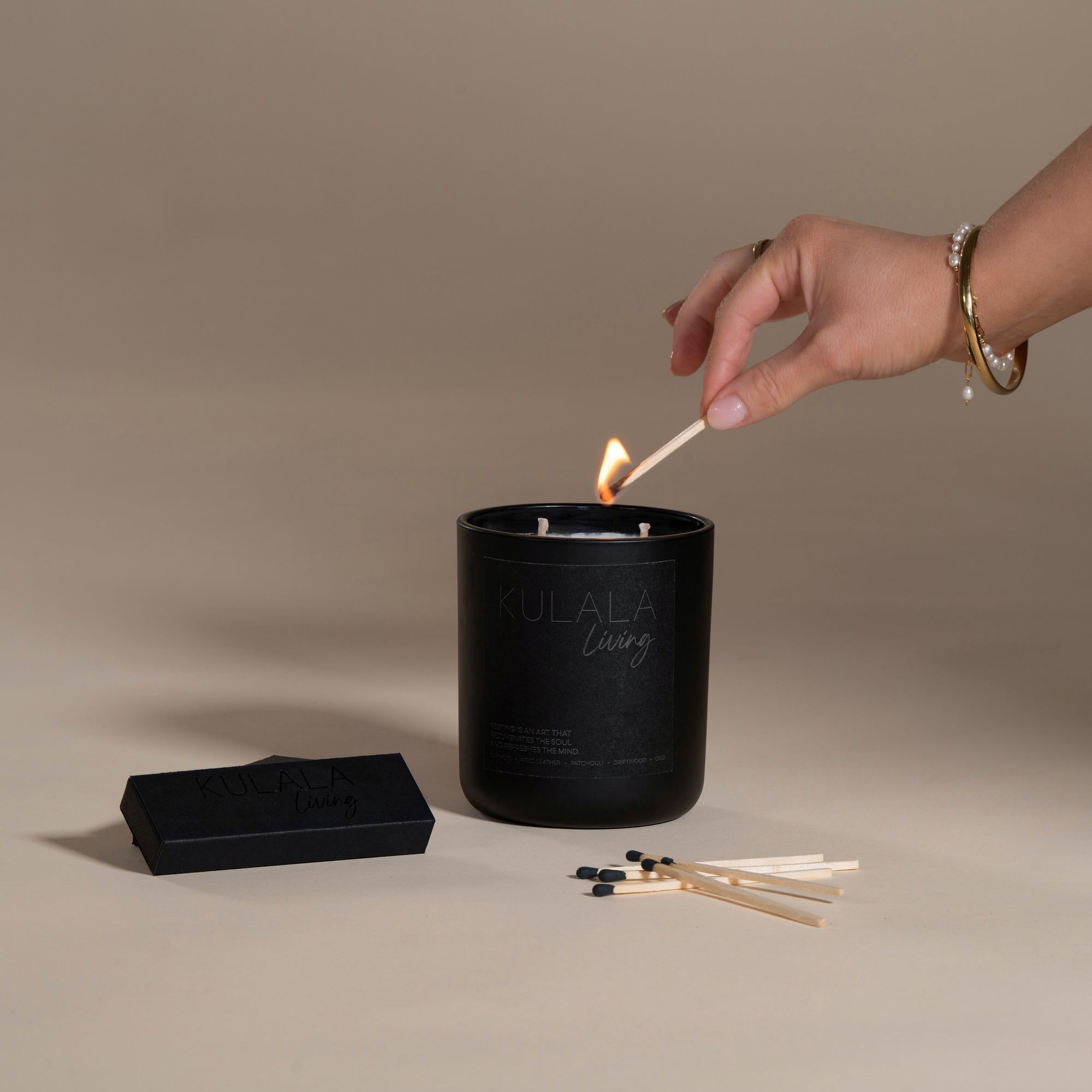 Kulala Living black matchbox with minimalist branding, featuring long wooden matches with black tips, set against a neutral backdrop for a refined aesthetic