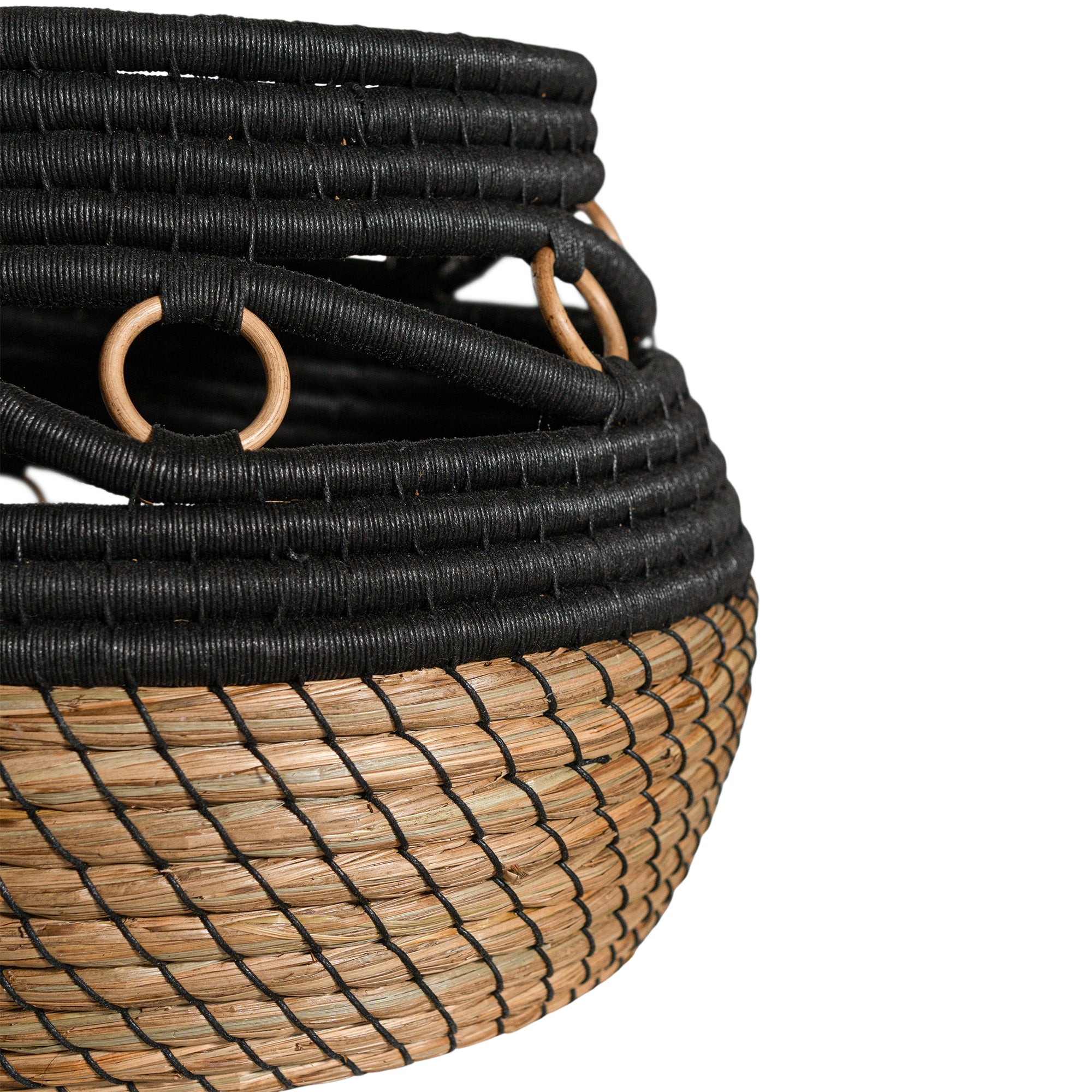 Black and natural woven basket with circular accents, ideal for decorative storage and adding texture to interior spaces.