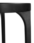 A sleek black oak round stool featuring a minimalist design with subtly curved legs. Crafted from solid oak with a matte black finish, this versatile piece functions as a stool or side table, adding a modern touch to any space