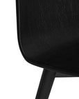 The Kulala Living black wood dining chair features a sleek, curved seat with a natural wood grain finish. Its minimalist design and sturdy legs make it a stylish and versatile addition to any modern dining space