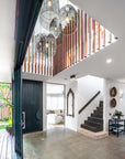 Cluster of black woven pendant lights in a modern foyer with timber panel accents and contemporary interior design.
