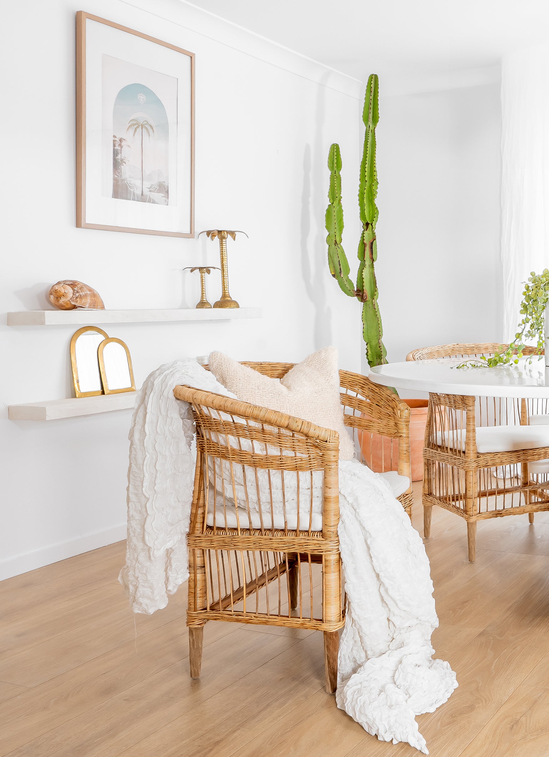 A beautifully styled natural rattan armchair with a white cushion, draped with a textured throw and paired with soft neutral décor, creating a warm and inviting boho-inspired interior.