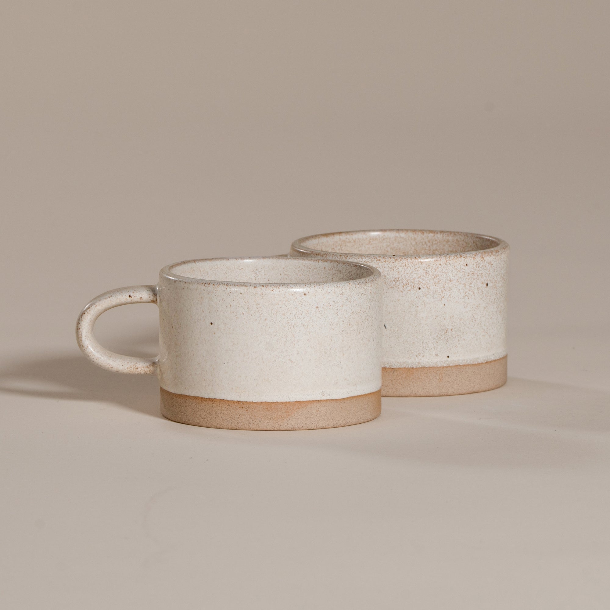 A beautifully handcrafted ceramic coffee mug and matching cup, featuring a minimalist stoneware design with a natural speckled glaze and raw clay base. Perfect for enjoying your morning coffee or tea in a timeless, artisanal style