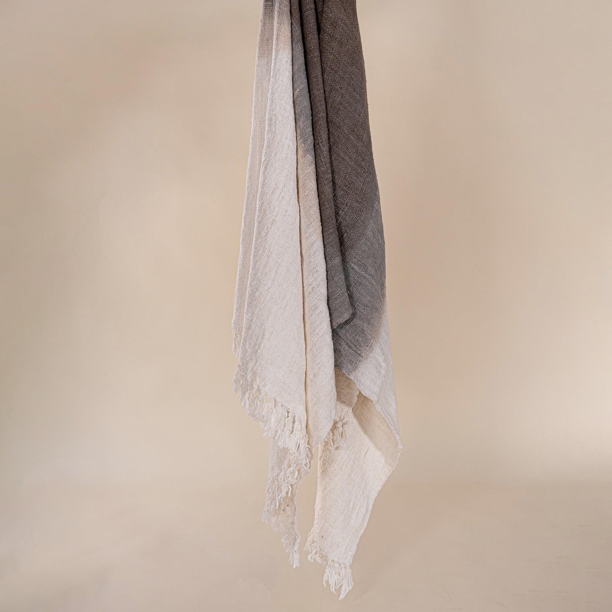 Soft cotton throw blanket in beige and brown with fringe detailing, adding a touch of natural texture to any living space