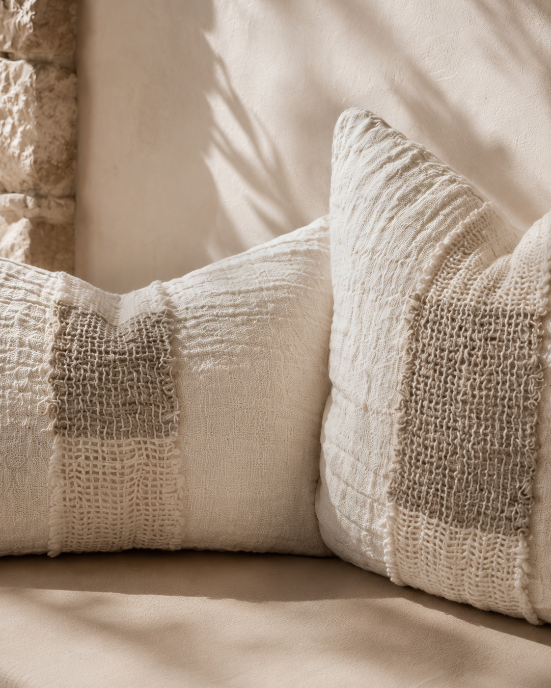 Dune rectangle and square cushions styled on a built in bench, showcasing soft woven textures and warm neutral tones in a relaxed Mediterranean inspired setting.