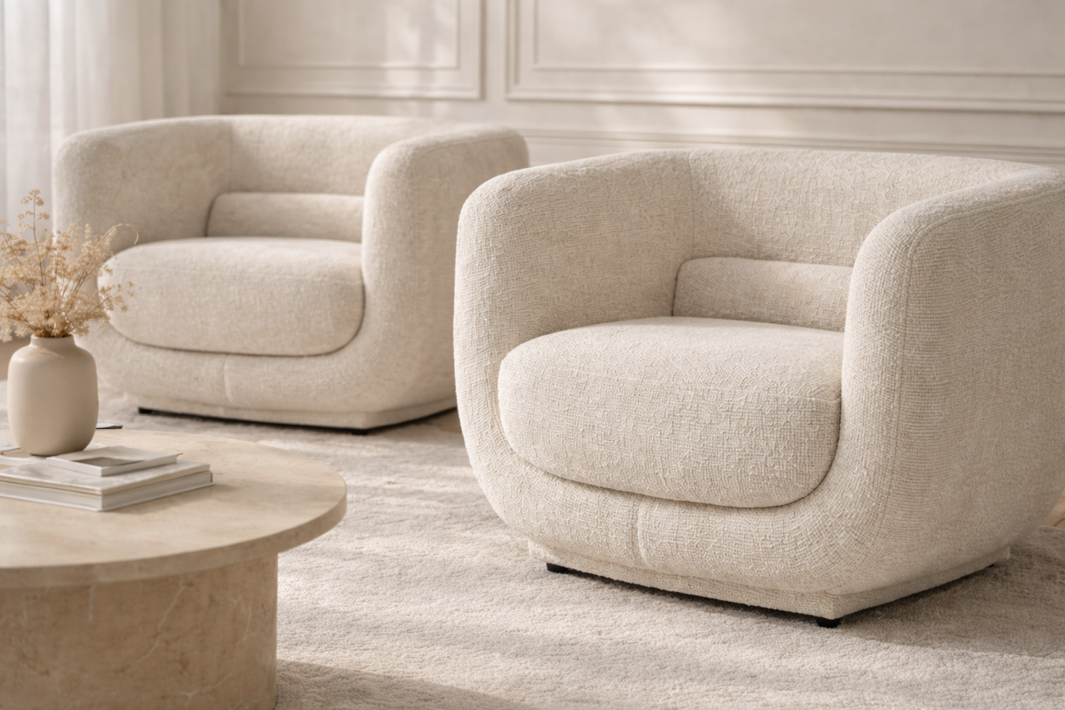 Francisco one seater armchairs in cream boucle with soft curved backs, styled in a refined neutral living room with a round marble coffee table and warm brass lamp accents.