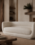 Francisco Sofa in Ivory bouclé creates a warm and inviting focal point beside a fireplace in a relaxed interior