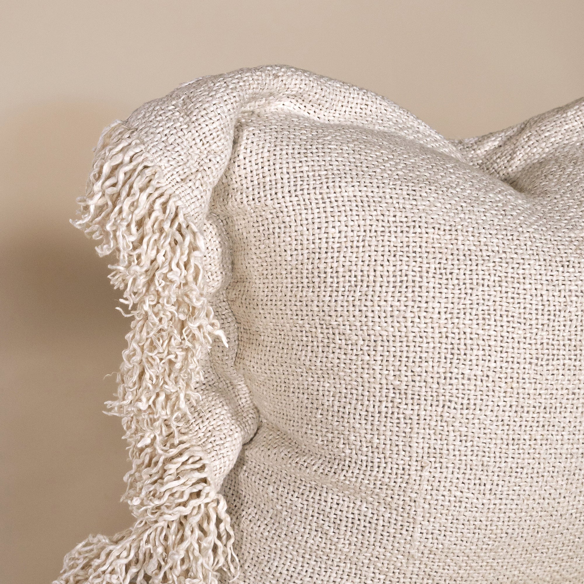 A beautifully textured handwoven linen cushion cover in a soft natural hue, featuring delicate fringe details for a relaxed, organic look. Ideal for layering on sofas or beds