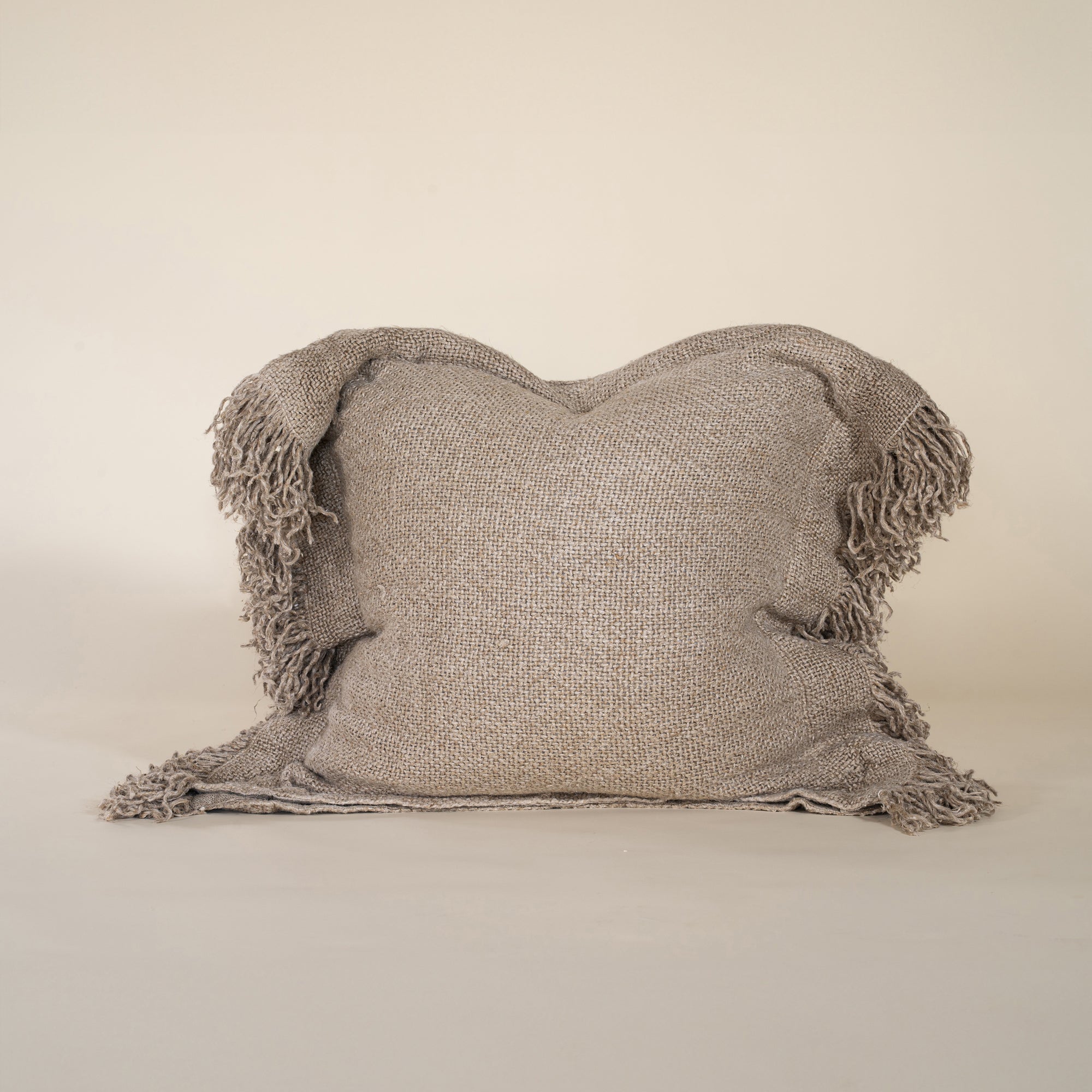 A beautifully textured handwoven linen cushion cover in a soft natural hue, featuring delicate fringe details for a relaxed, organic look. Ideal for layering on sofas or beds