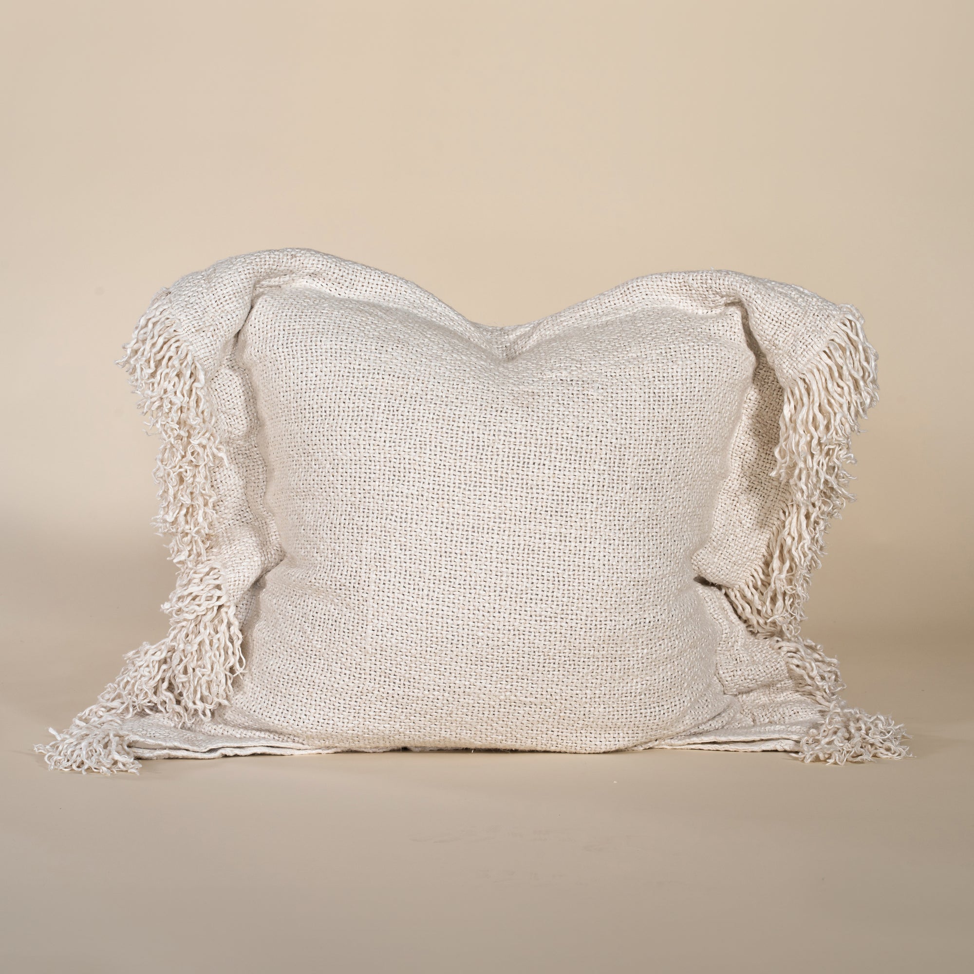 A beautifully textured handwoven linen cushion cover in a soft natural hue, featuring delicate fringe details for a relaxed, organic look. Ideal for layering on sofas or beds