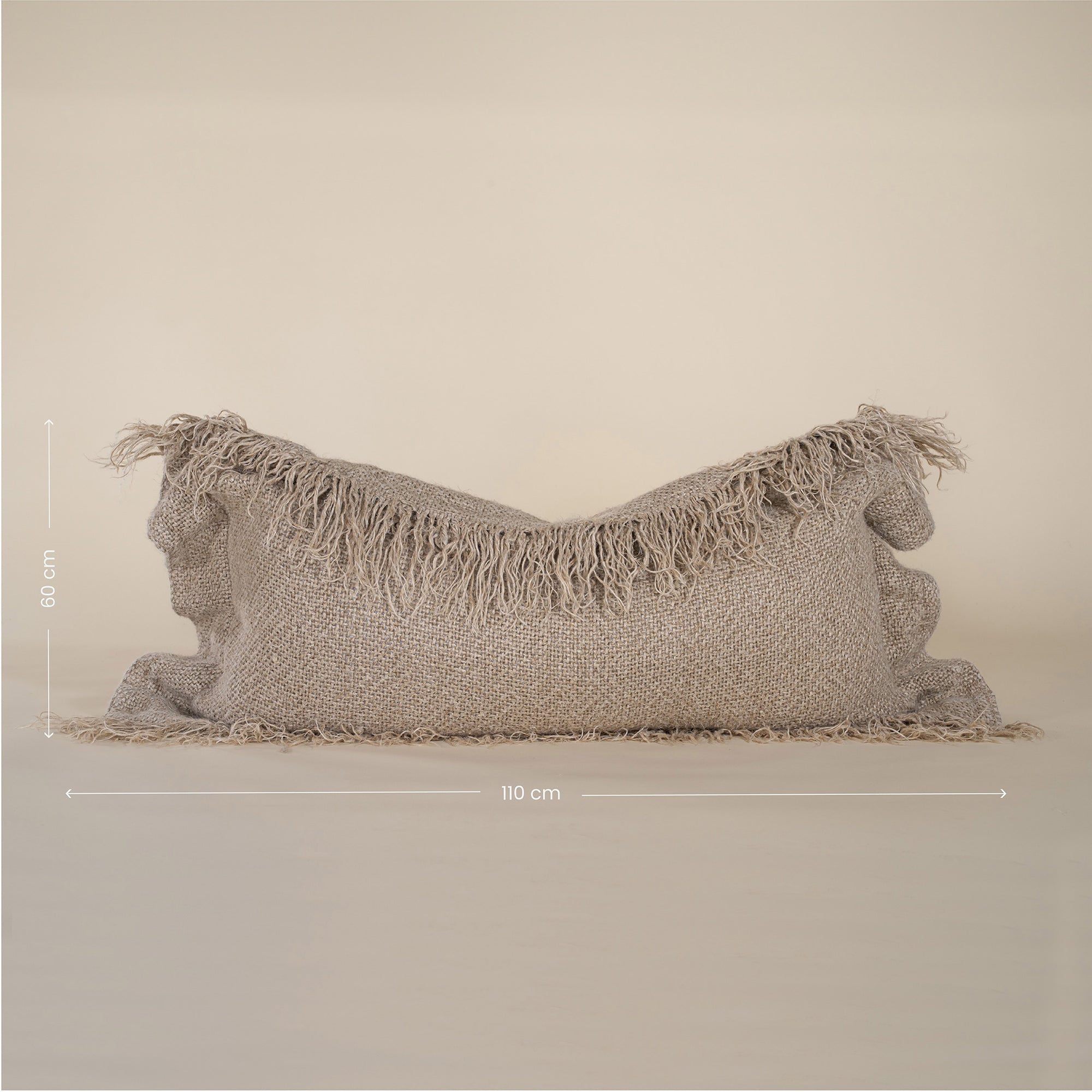 A natural-toned lumbar cushion with a woven texture, featuring delicate fringed edges, set against a neutral backdrop