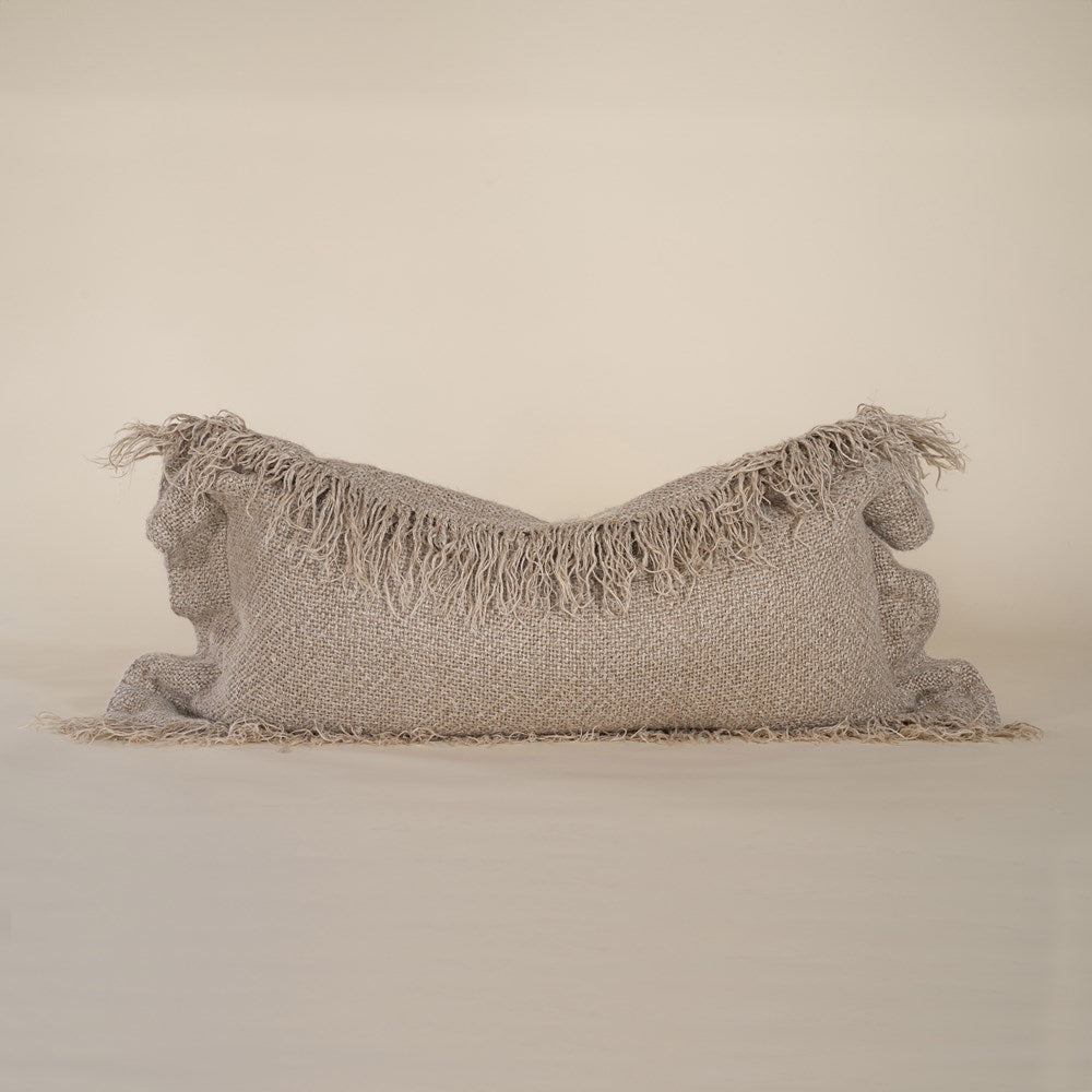 A natural-toned lumbar cushion with a woven texture, featuring delicate fringed edges, set against a neutral backdrop