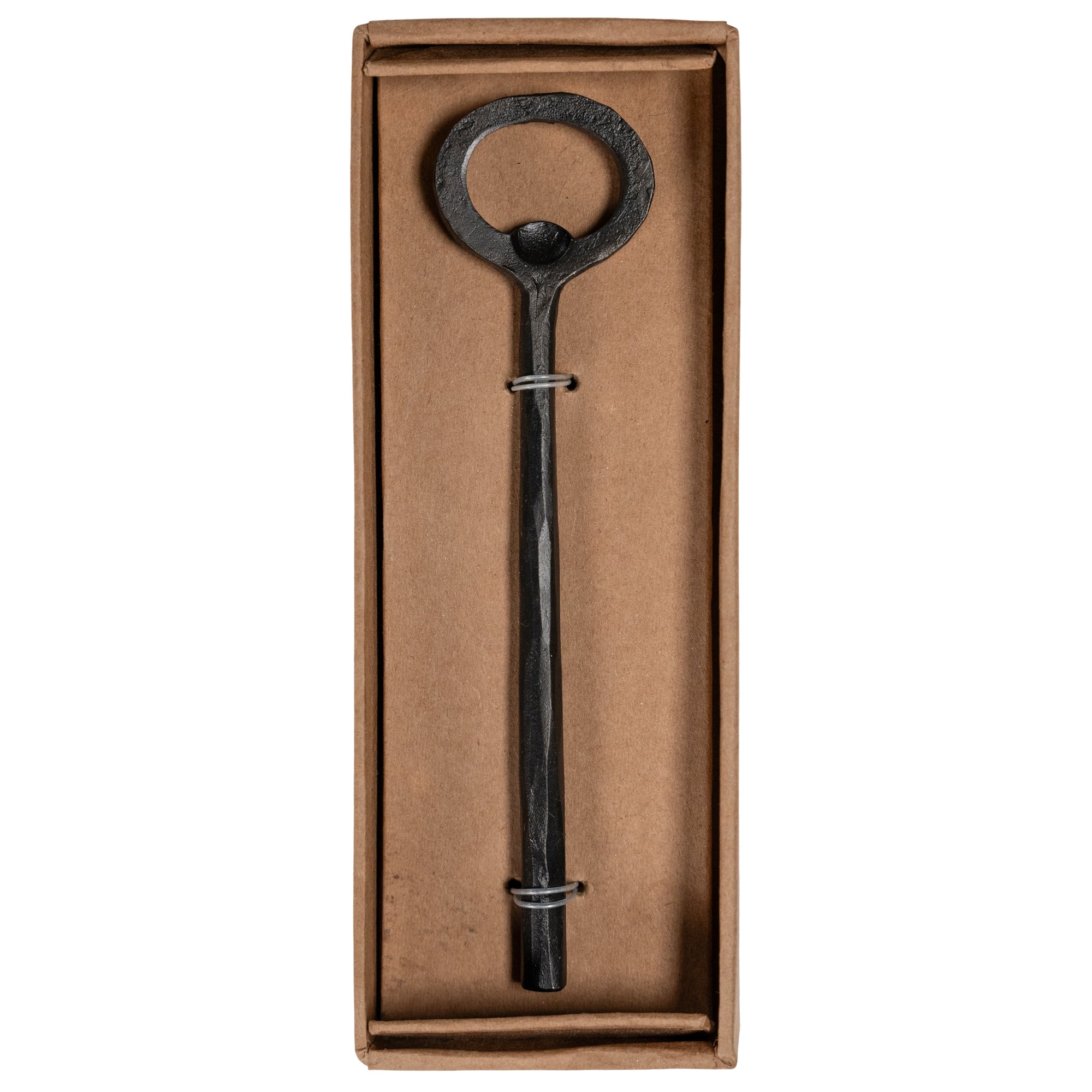 A handcrafted black iron bottle opener with a rustic finish, presented in a minimalist brown cardboard box