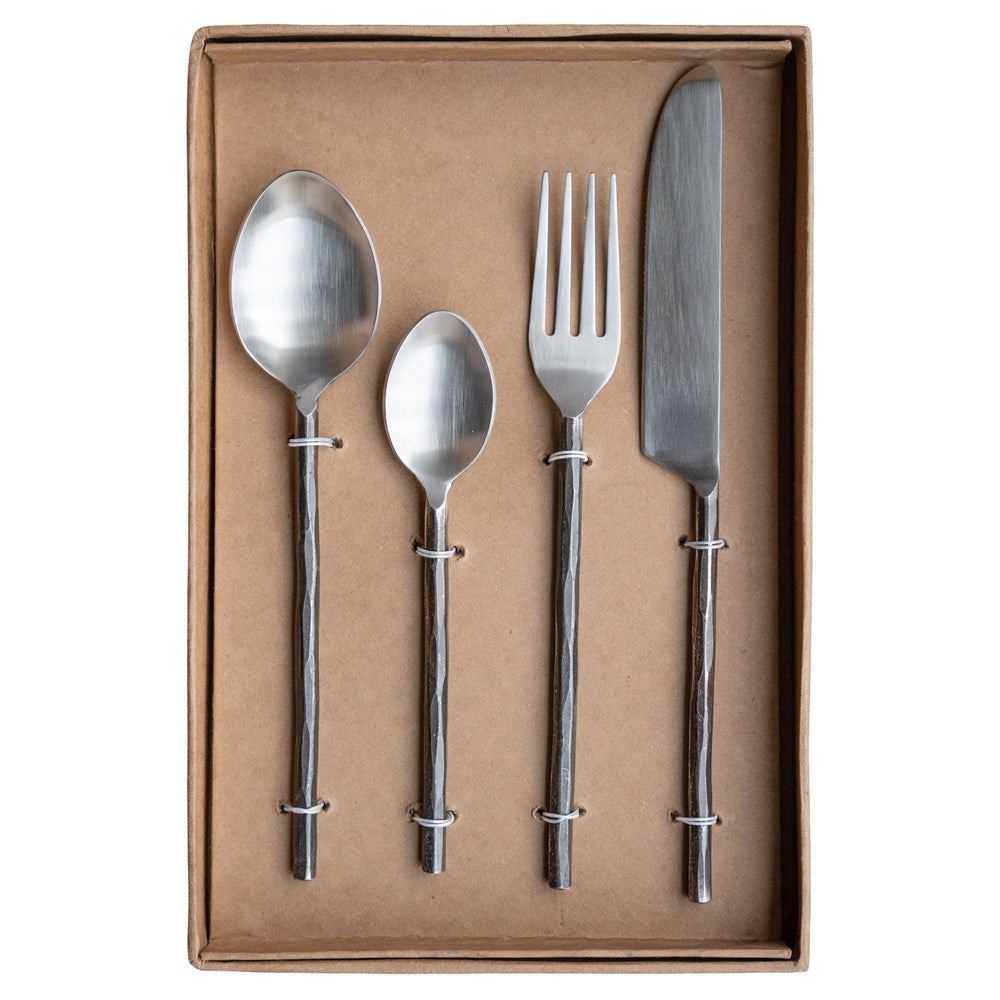 A set of four handcrafted stainless steel cutlery pieces with hand-forged handles, elegantly presented in a minimalist kraft gift box. Includes a dinner knife, fork, tablespoon, and teaspoon for a refined dining
