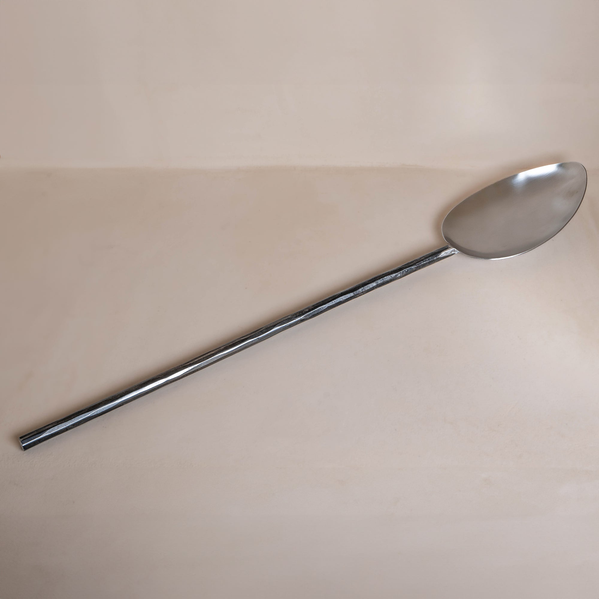 A handcrafted iron cooking spoon from KULALA Living, featuring a long black metal handle and a polished stainless steel scoop, perfect for stirring and serving with ease