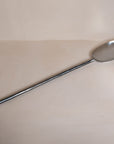 A handcrafted iron cooking spoon from KULALA Living, featuring a long black metal handle and a polished stainless steel scoop, perfect for stirring and serving with ease