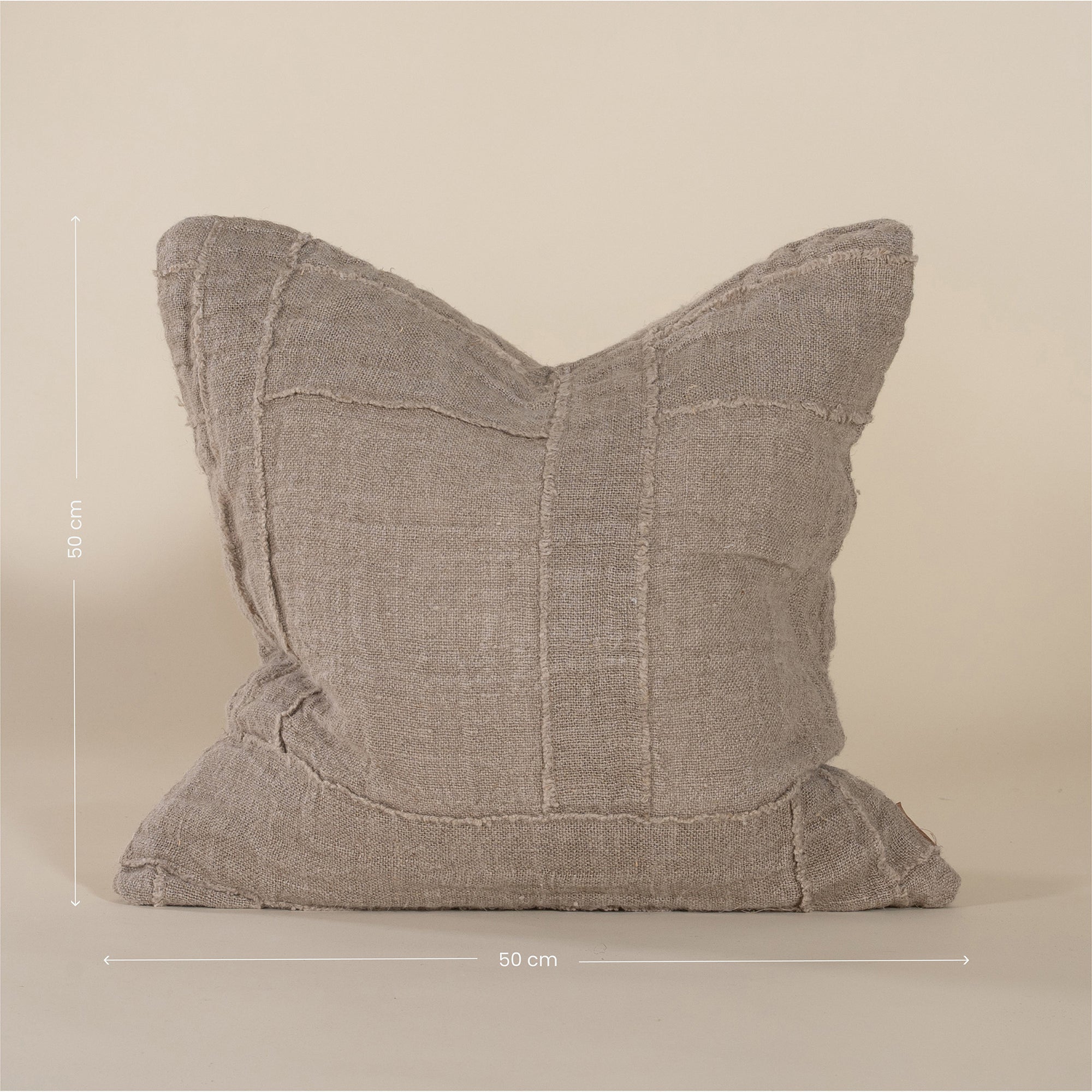 Soft natural linen cushion with a hand-stitched patchwork design, adding texture and warmth to any living space