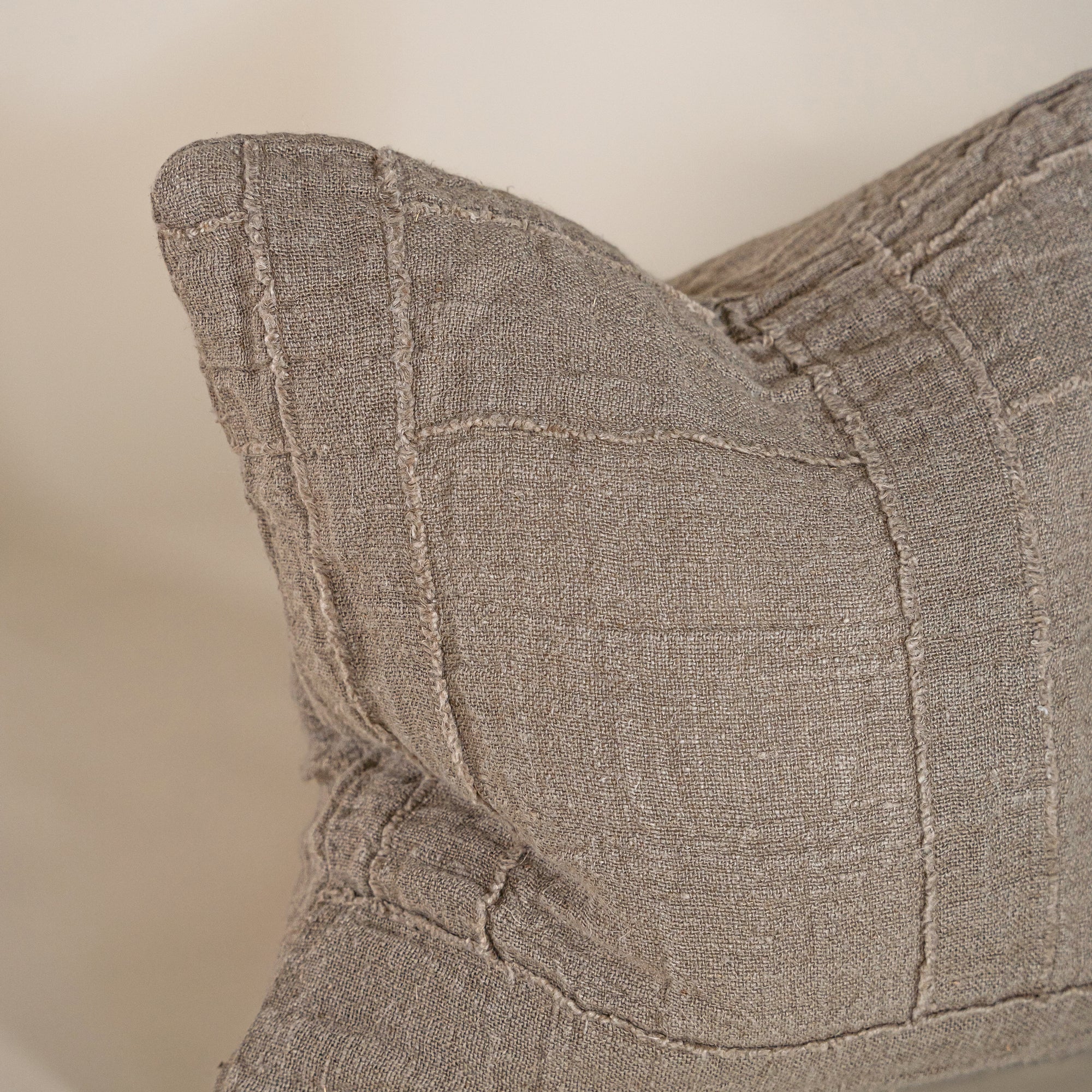 Soft natural linen cushion with a hand-stitched patchwork design, adding texture and warmth to any living space
