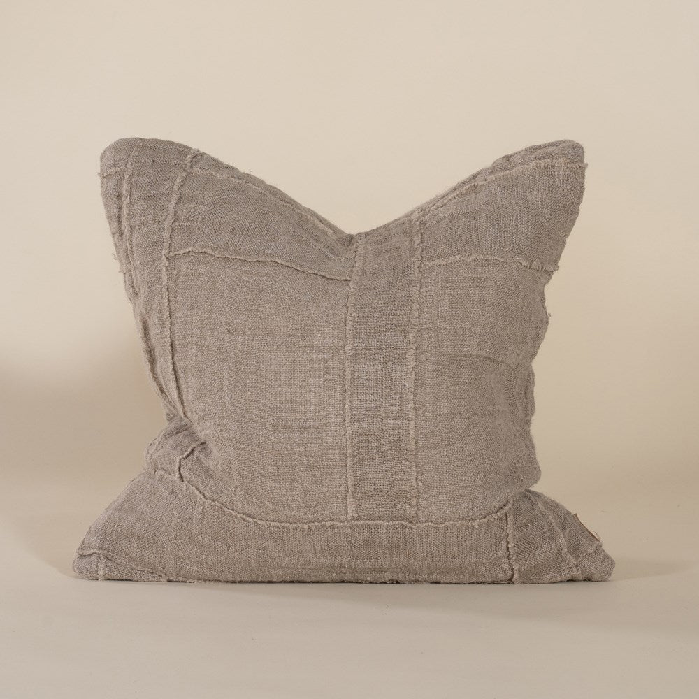Soft natural linen cushion with a hand-stitched patchwork design, adding texture and warmth to any living space