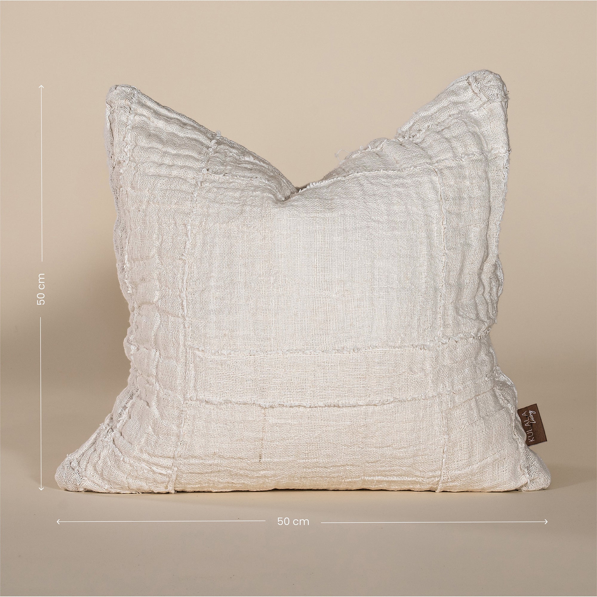 Soft off-white linen cushion with a hand-stitched patchwork design, adding texture and warmth to any living space