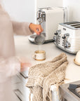 KULALA Living handwoven natural linen tea towel styled in a warm kitchen moment with ceramic mug and coffee preparation.