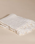 An elegant off-white handwoven linen throw from KULALA Living, featuring a soft texture and delicate fringed edges. A perfect layering piece for a relaxed, stylish home