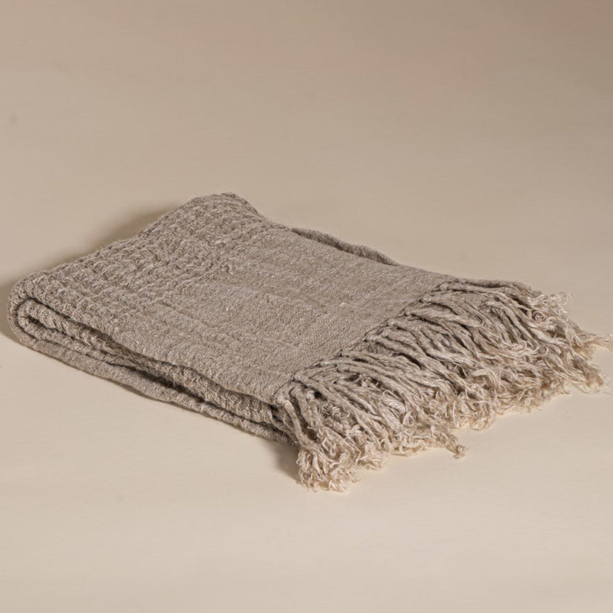 A beautifully handwoven linen throw from KULALA Living, featuring a soft texture and elegant fringed edges. Perfect for layering warmth and style in any space