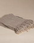 A beautifully handwoven linen throw from KULALA Living, featuring a soft texture and elegant fringed edges. Perfect for layering warmth and style in any space
