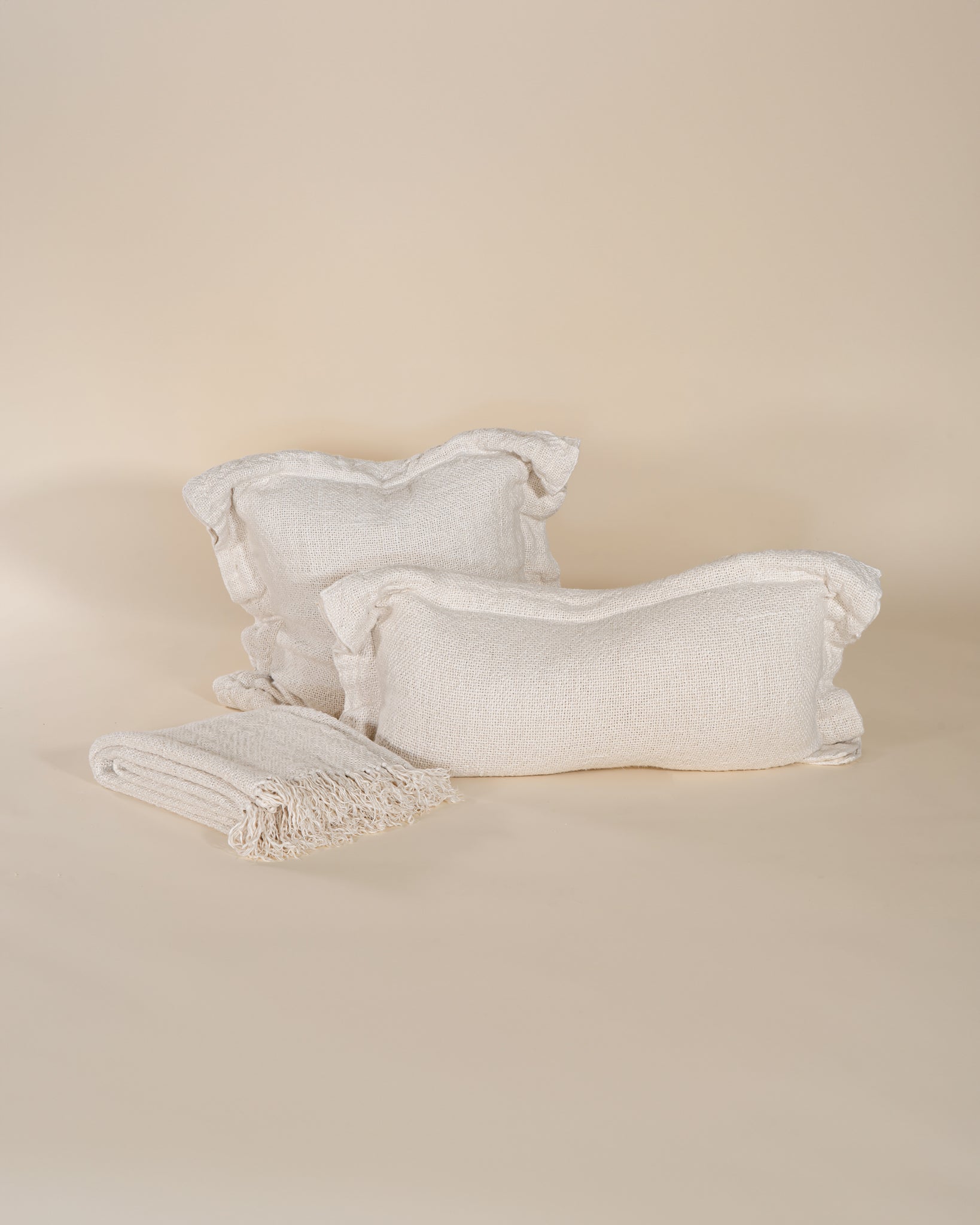A soft, handwoven linen cushion cover in a natural off-white hue, featuring a relaxed, textured finish. Perfect for adding an organic touch to any living space