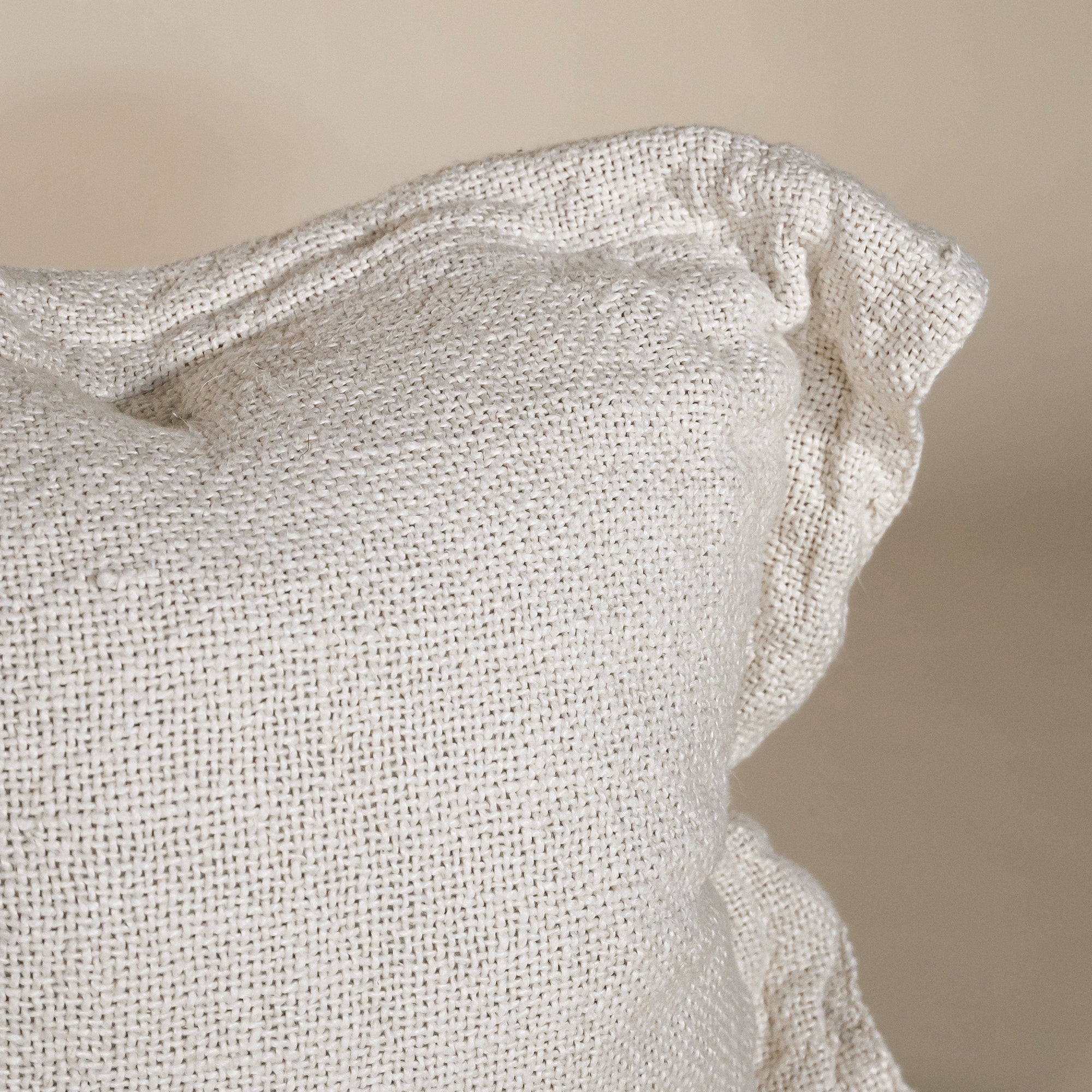 A soft, handwoven linen cushion cover in a natural off-white hue, featuring a relaxed, textured finish. Perfect for adding an organic touch to any living space